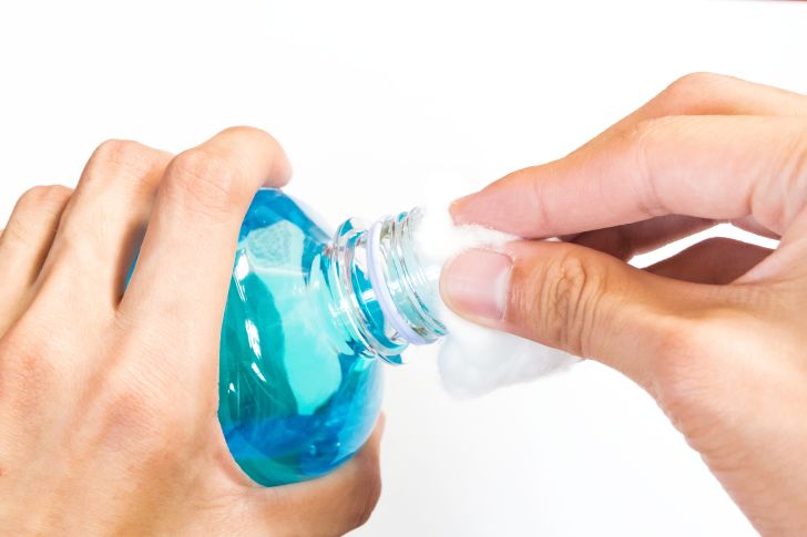 Bottle of rubbing alcohol with cotton ball.