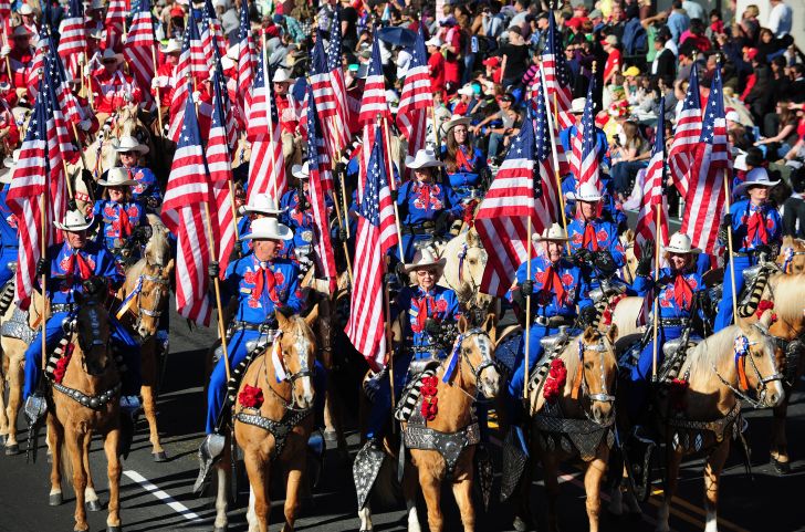 Participants on horseback hold U.S. flags during the annual Tournament of Roses Parade in Pasadena