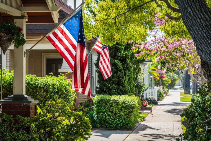 Two flags hanging from houses on a quiet street.