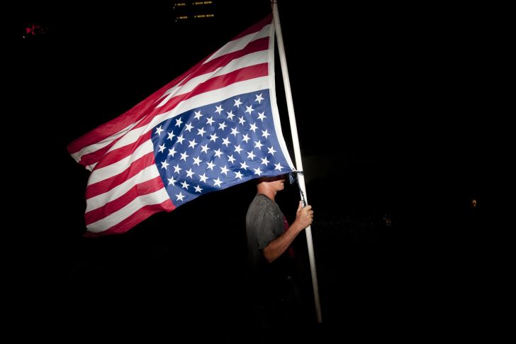 A protester marches with an upside-down American flag.