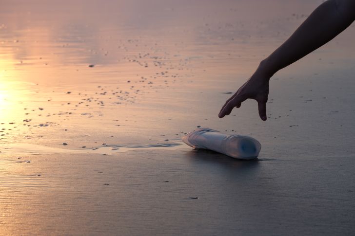 Picking up a bottle on the beach