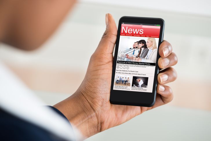 A person reading the news on their phone.