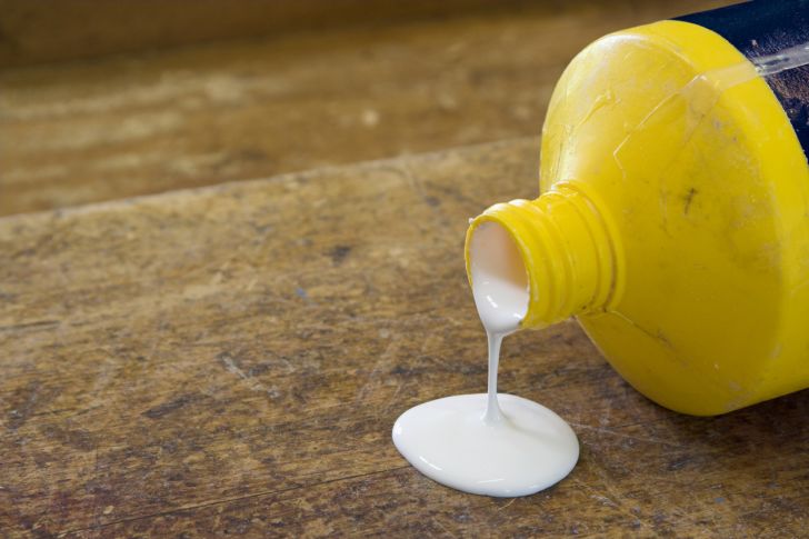 glue spilling from bottle onto wood table