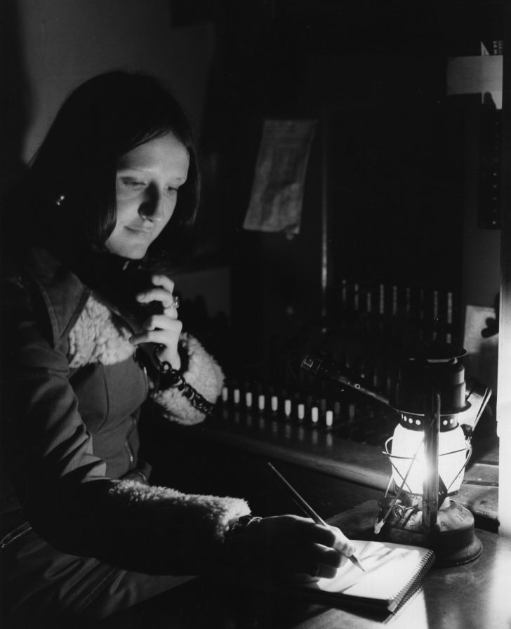 A telephone operator works by hurricane lamp because of energy crisis restrictions in 1974.