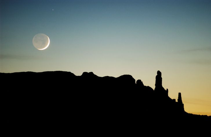 The moon sets over sandstone formations near Round Rock on the Navajo Indian Reservation, Arizona.