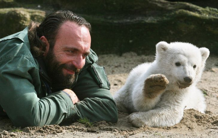 Knut and his handler pose for photos lying down on their bellies.