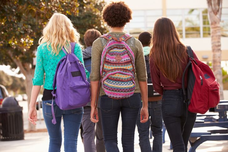 Three women wearing backpacks.