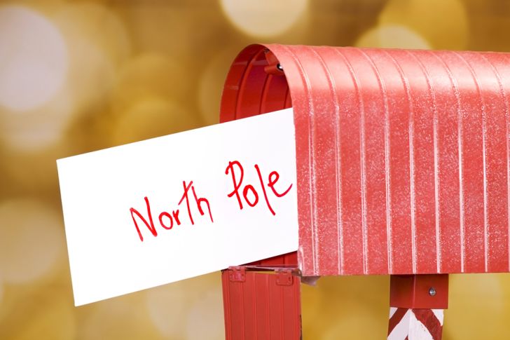 An evelope that reads 'North Pole' sticks out from a red mailbox.