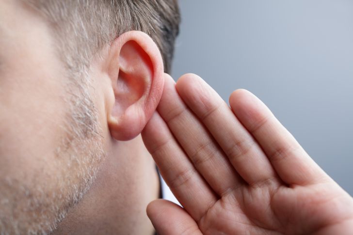 A man's hand next to his ear.