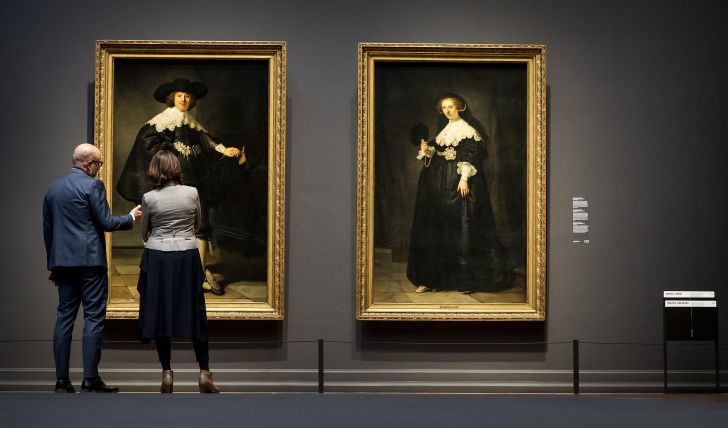 Two visitors look at Marten and Oopjen, two Rembrandt portraits of a wedding couple