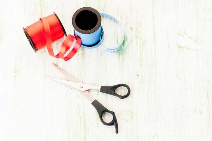 Two rolls of ribbon and a pair of scissors on a white background.
