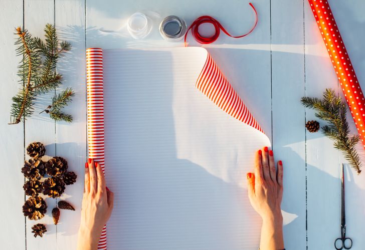 A person measuring out wrapping paper.