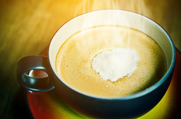 Powdered coffee creamer is shown dissolving in a cup of coffee