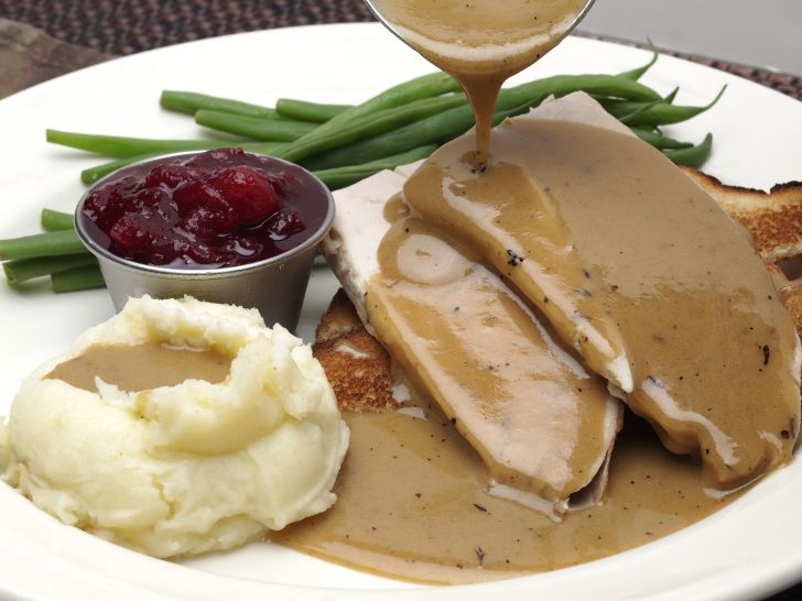 Plate of turkey and potatoes covered in gravy.