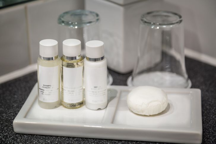 Hotel bathroom counter with cups, shampoo, and soap