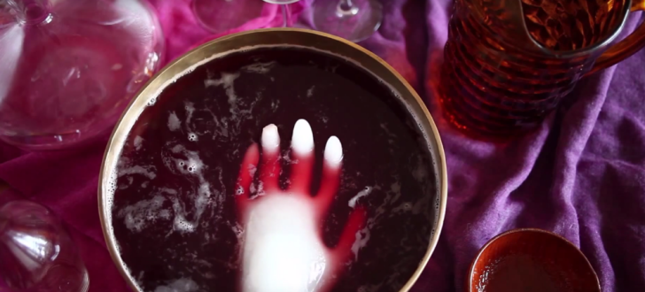 A hand-shaped block of ice floats in a punch bowl