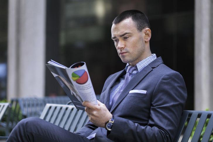 A young man in a business suit reading the paper