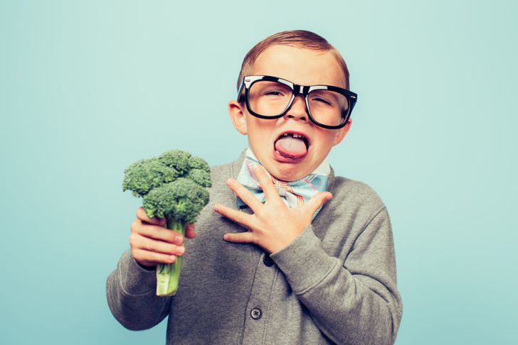 Young boy in oversized black glasses and bow tie with a head of broccoli expressing disgust