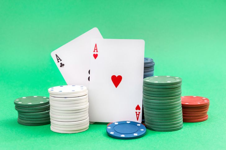 A pair of aces and stacks of poker chips on a green background