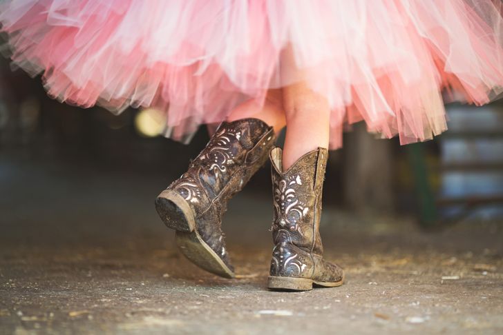 The lower half of a person in a pink tutu and cowgirl boots