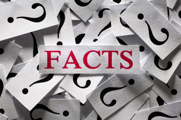 the word facts printed ona slip of paper in red ink surrounded by slips with question marks in black ink