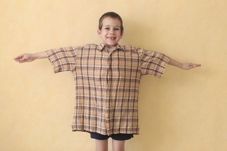 A little boy with his arms spread out, wearing an oversized t-shirt