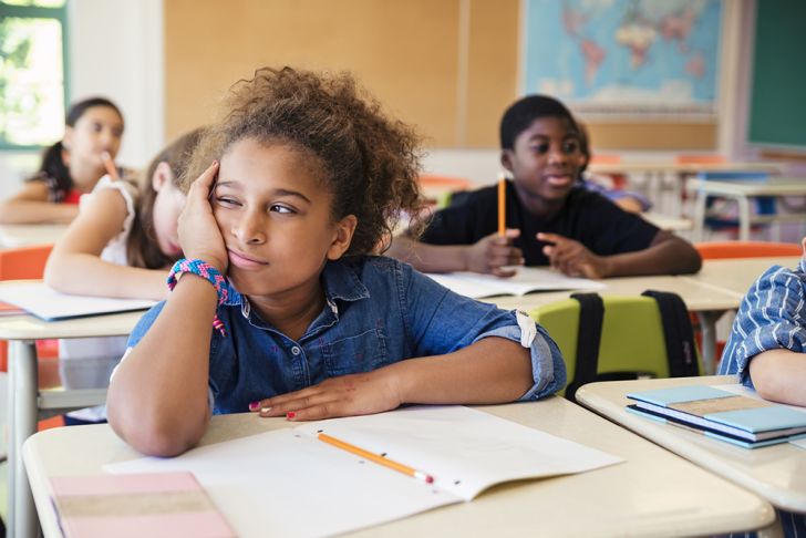 A bored little girl in an elementary classroom
