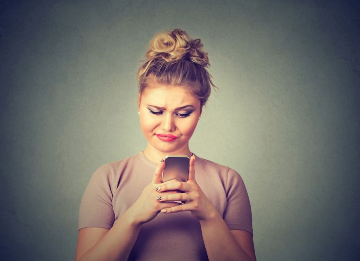 A skeptical woman texting on a phone