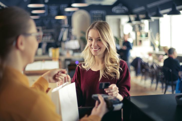 A young blond woman paying with a credit card at a shop