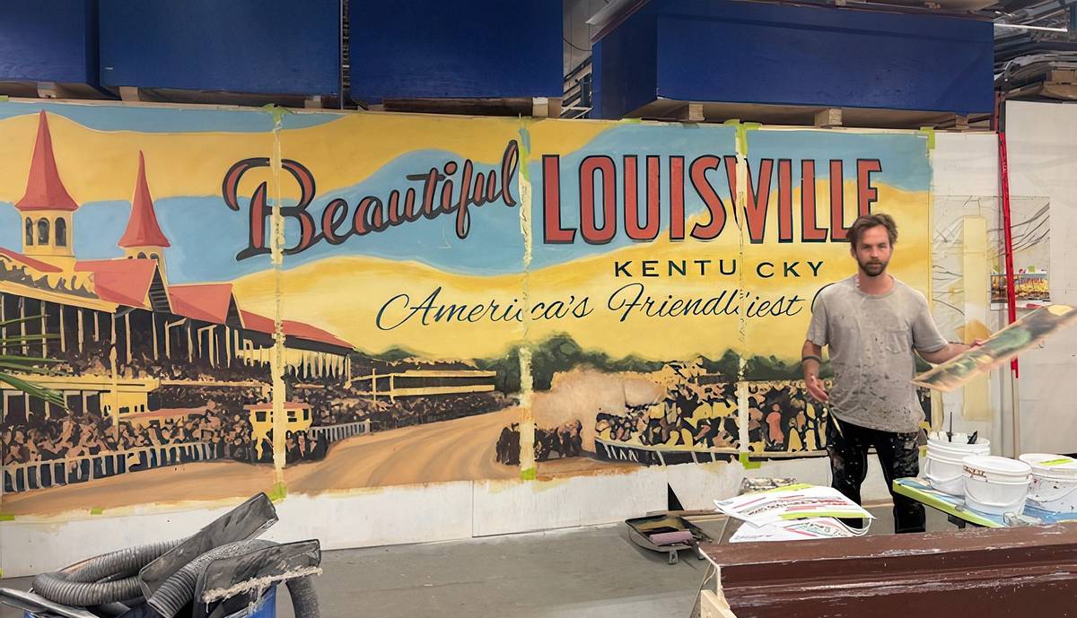 A scenic painter stands beside a large hand-painted mural reading "Beautiful Louisville, Kentucky, America's Friendliest City," showing the twin spires of Churchill Downs.