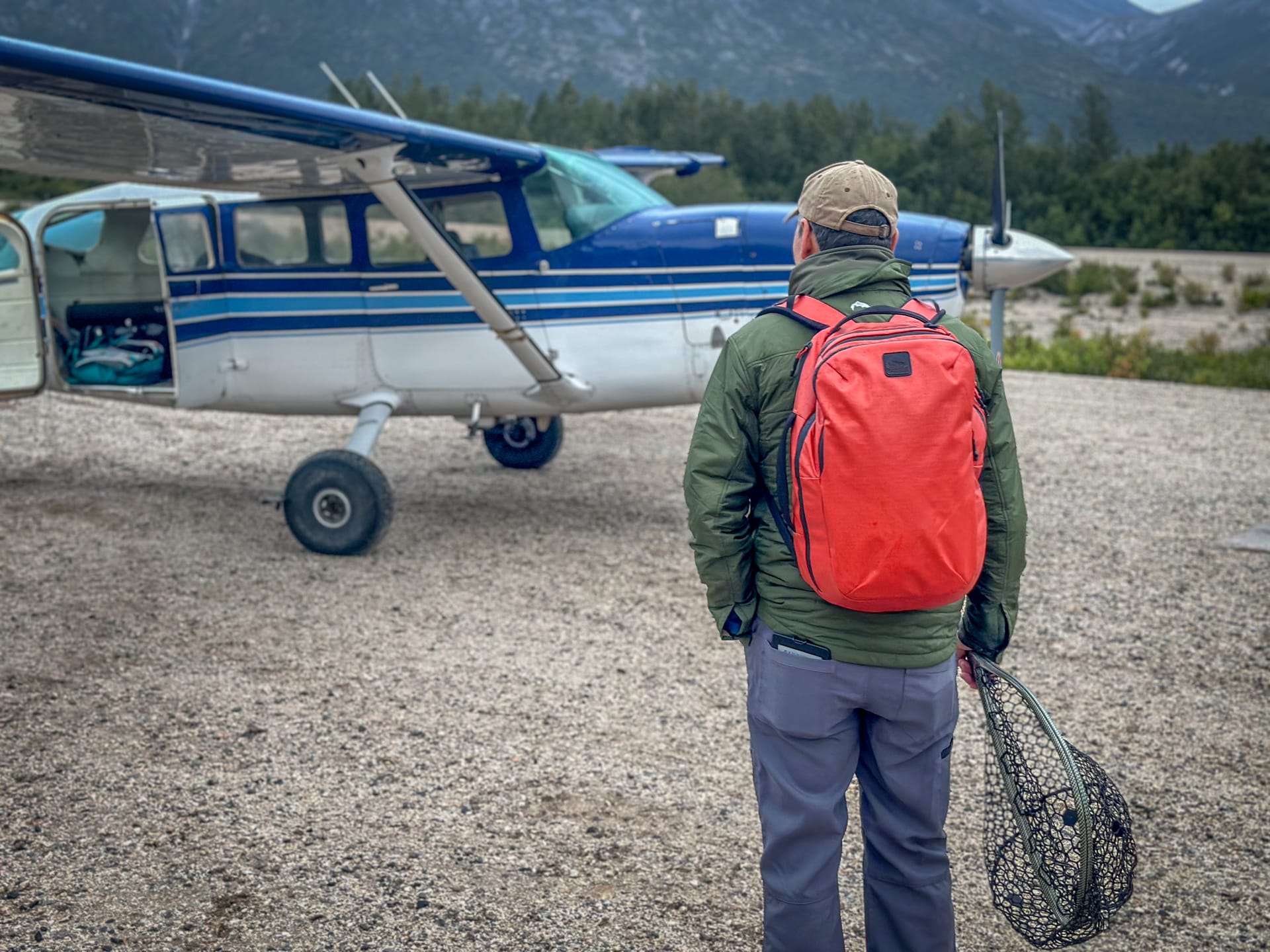 An angler waits on a gravel runway before he boards a small plane to fly out of the interior of Alaska.