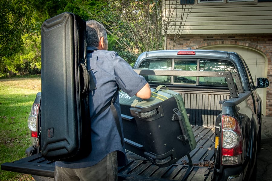 A fly angler loading up his pickup truck with luggage. 