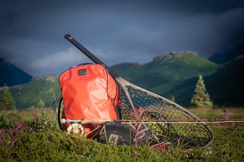 A Simms Tailwind backpack, net, and rod and reel resting on the Tundra in Alaska