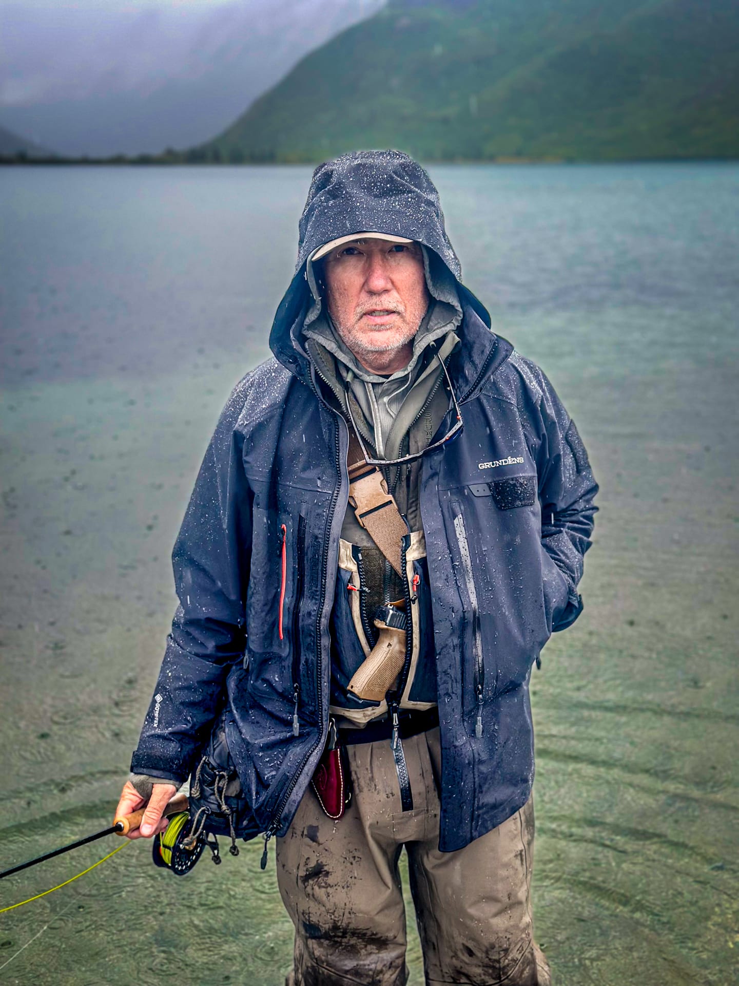 A fly angler wearing a Grundens technical wading jacket in the rain. 