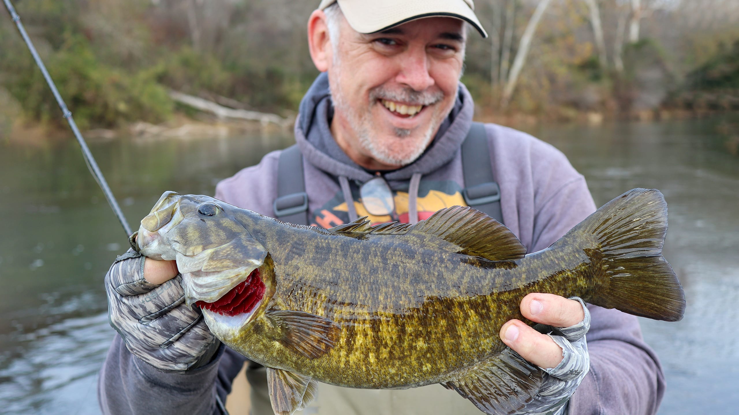 Angler holding a big smallmouth bass, showcasing success with simple fishing methods.