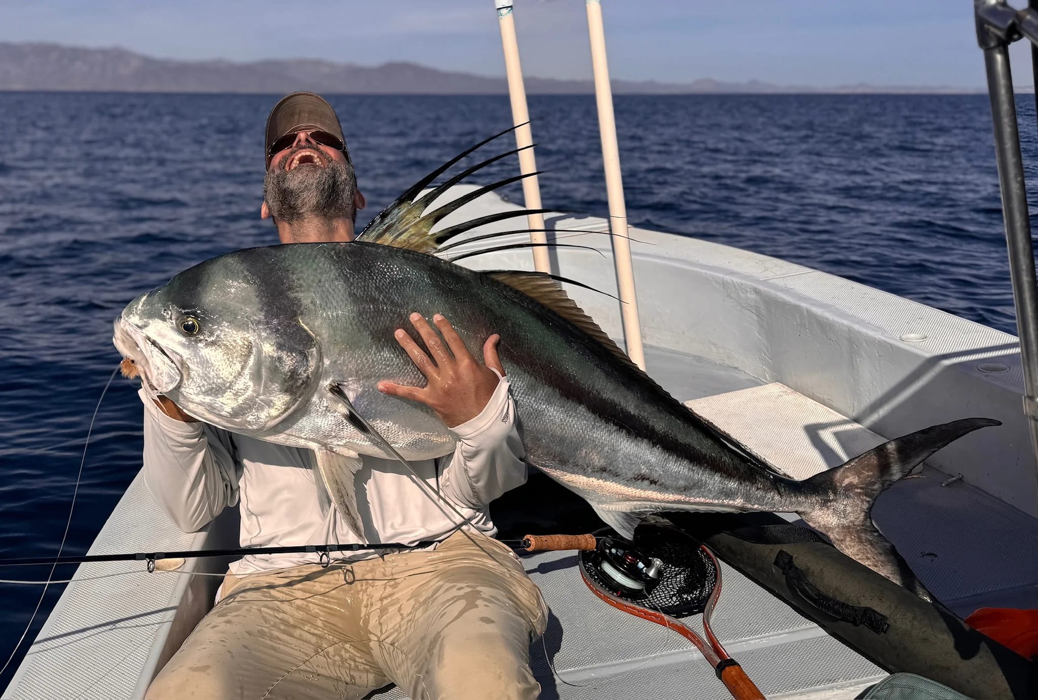 A fly angler holds a big roosterfish as he celebrates his catch on the Baja Coast. 