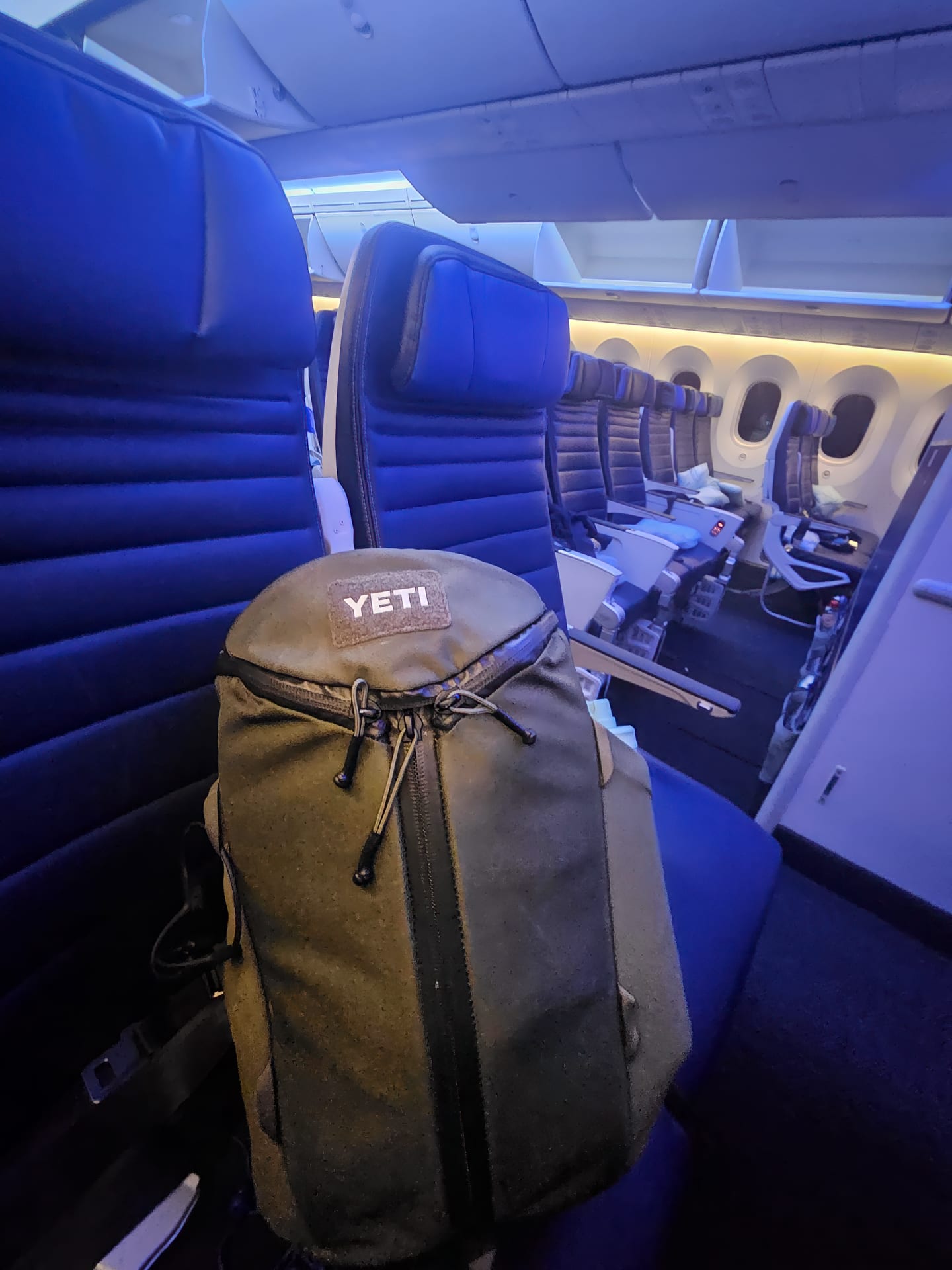The YETI Ranchero backpack in a passenger's seat on a commercial airline. 