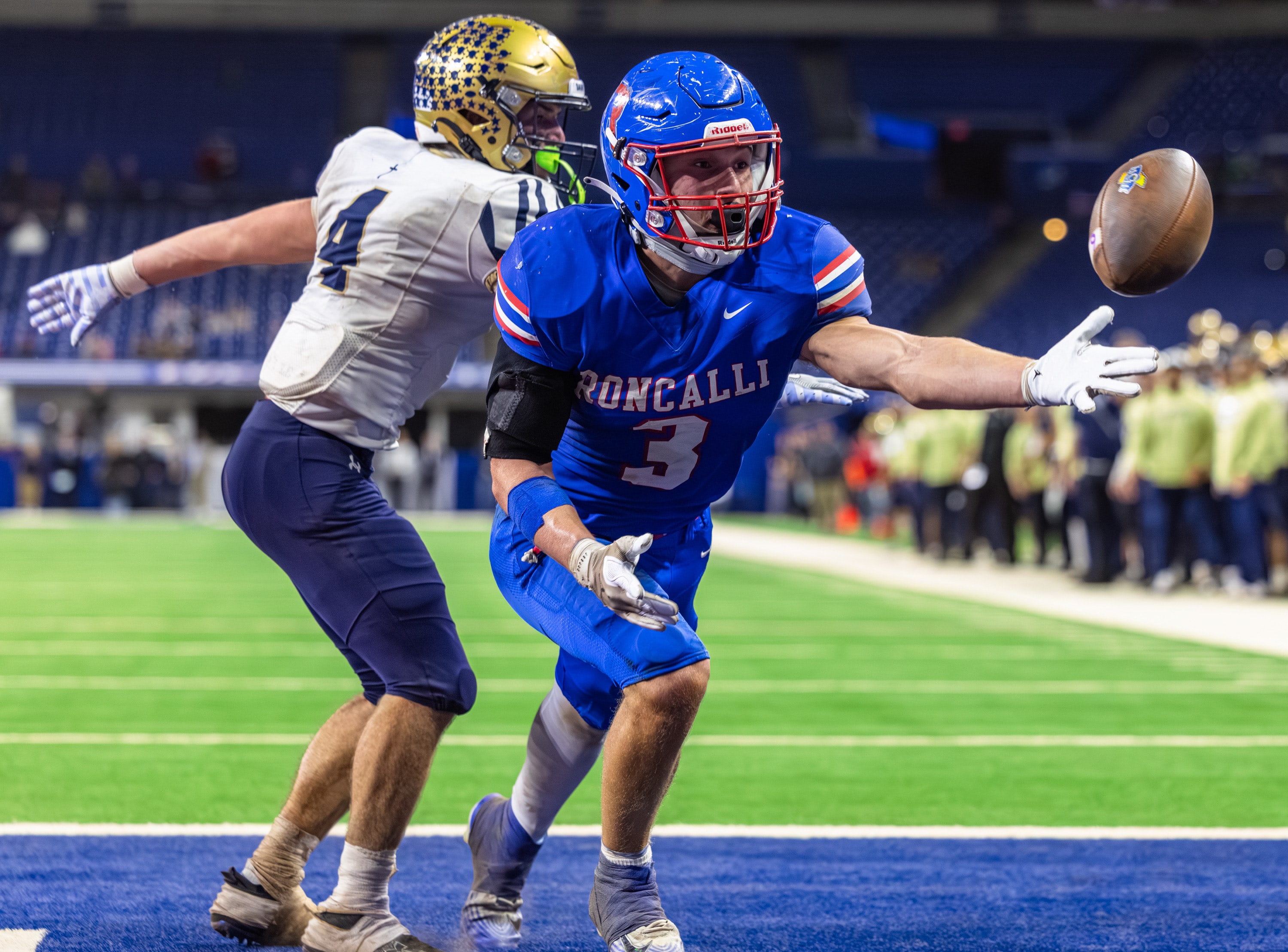 A Roncalli player lunges for a game tying grab past a Dwenger defender in an Indiana high school football game.