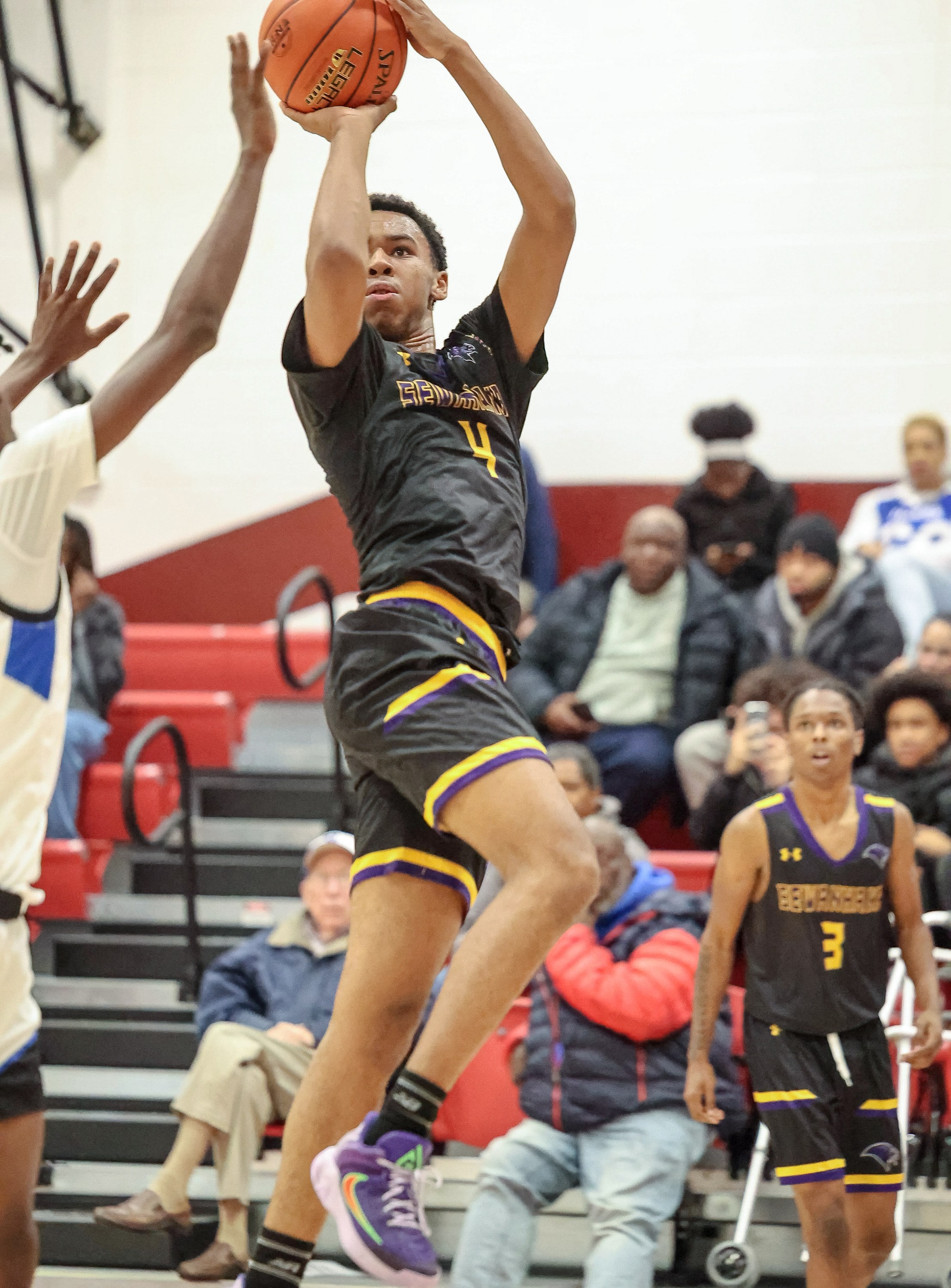 A Sewanhaka player rises for an off-balance runner over the Hempstead defender in a New York high school basketball game.