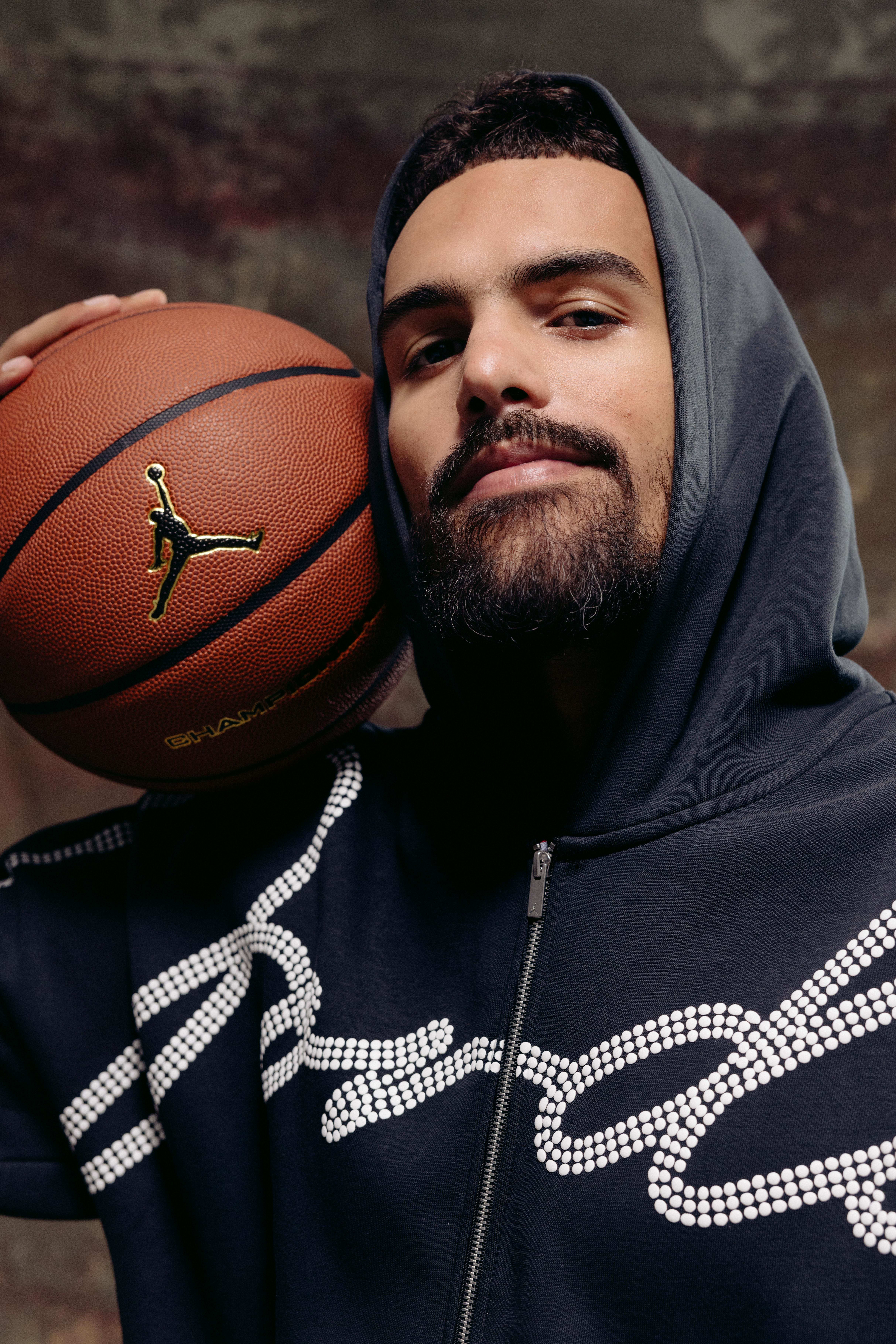 Trae Young holds a basketball in a photo shoot.