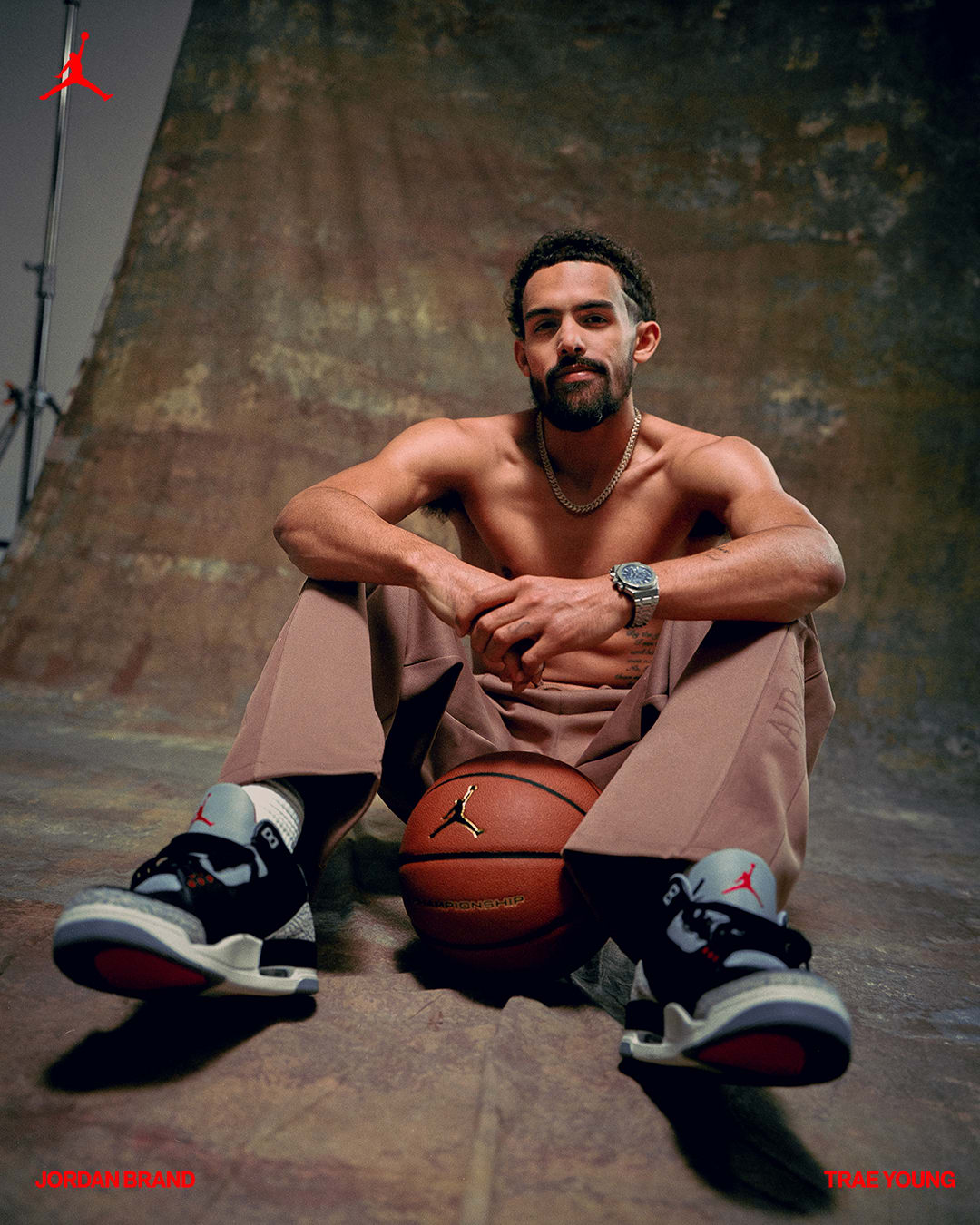 Trae Young sits with a basketball in a photo shoot.