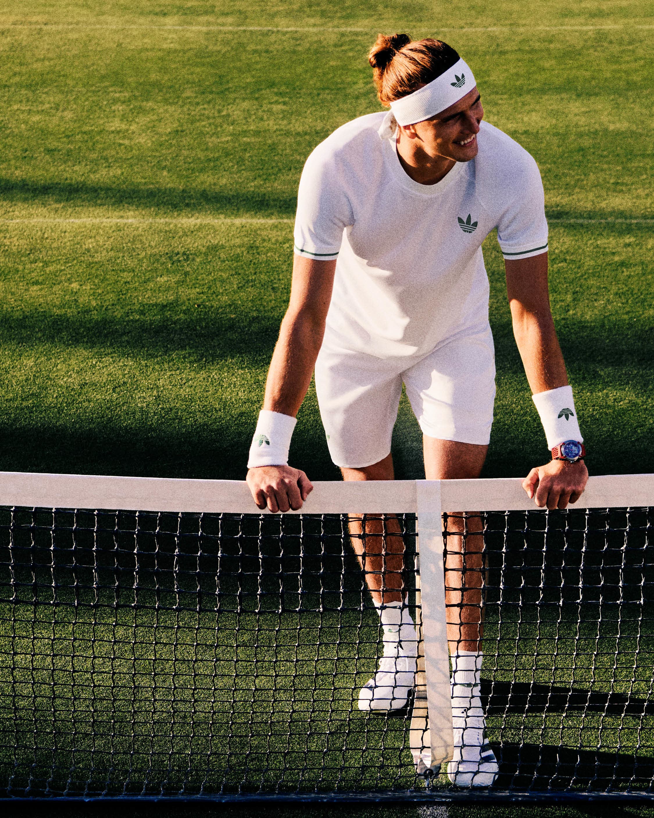 Alexander Zverev models adidas tennis apparel on a grass court.