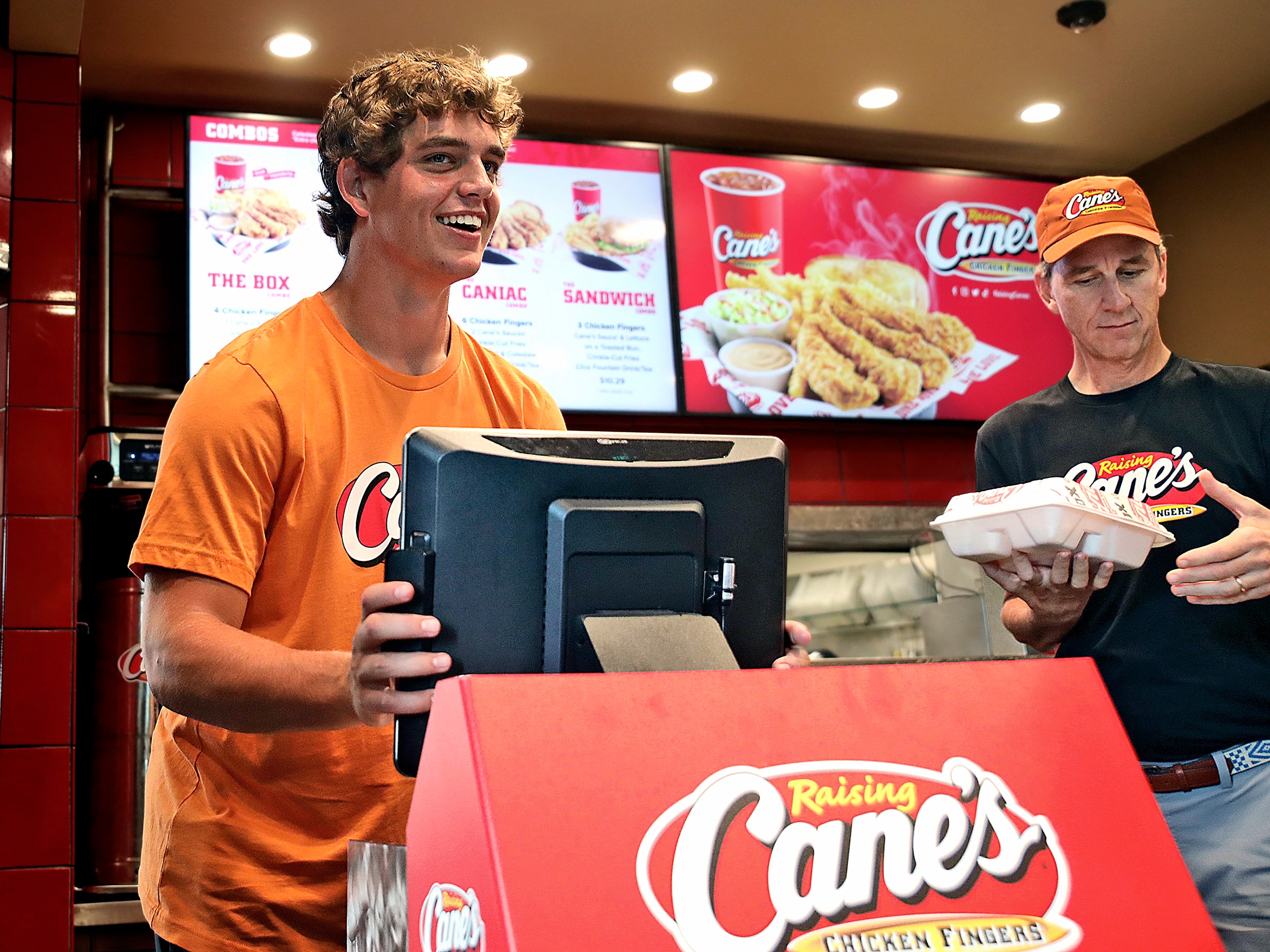 Arch and Cooper Manning work the register at Raising Cane’s.