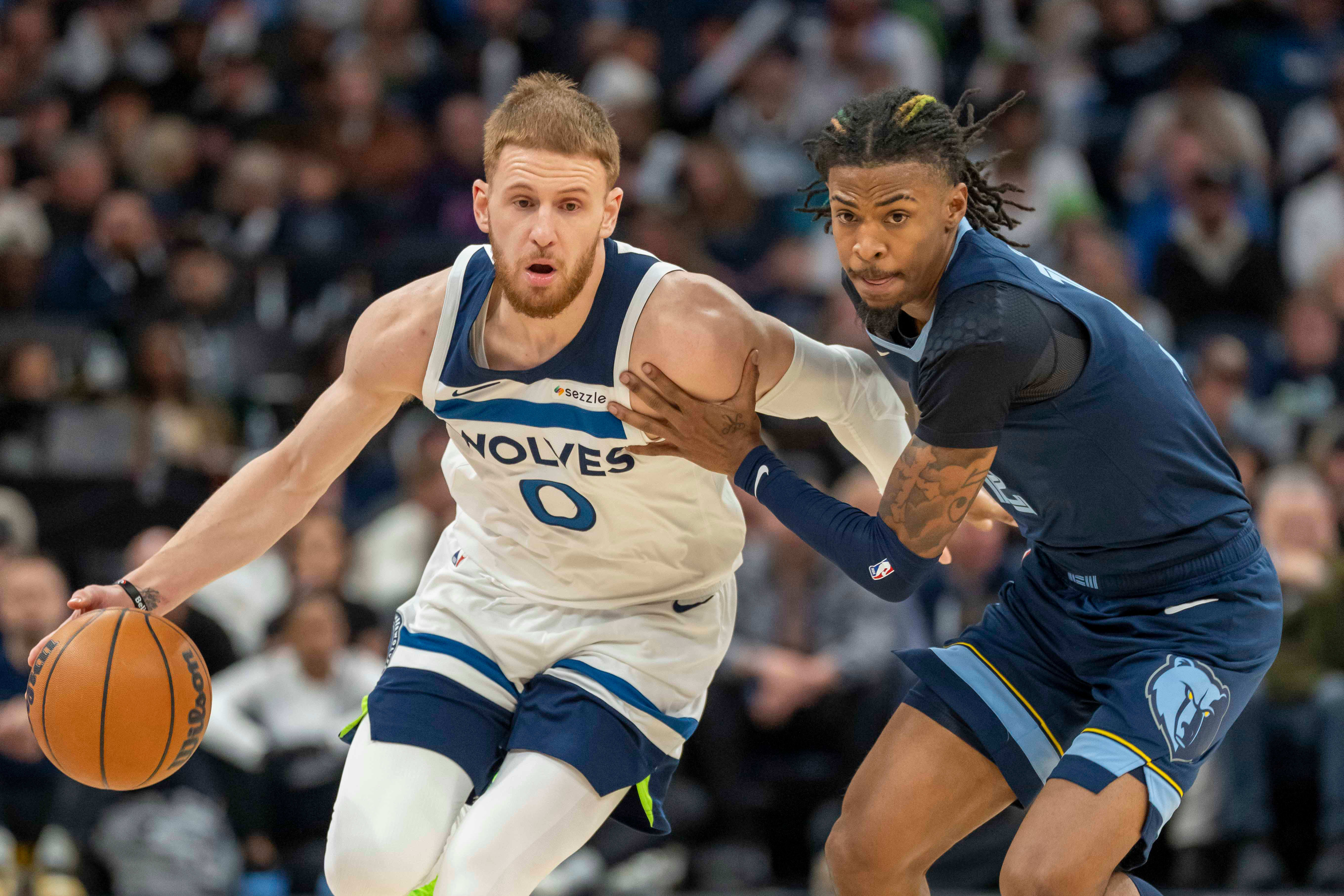 Minnesota Timberwolves shooting guard Donte DiVincenzo dribbles the ball against Memphis Grizzlies guard Ja Morant.