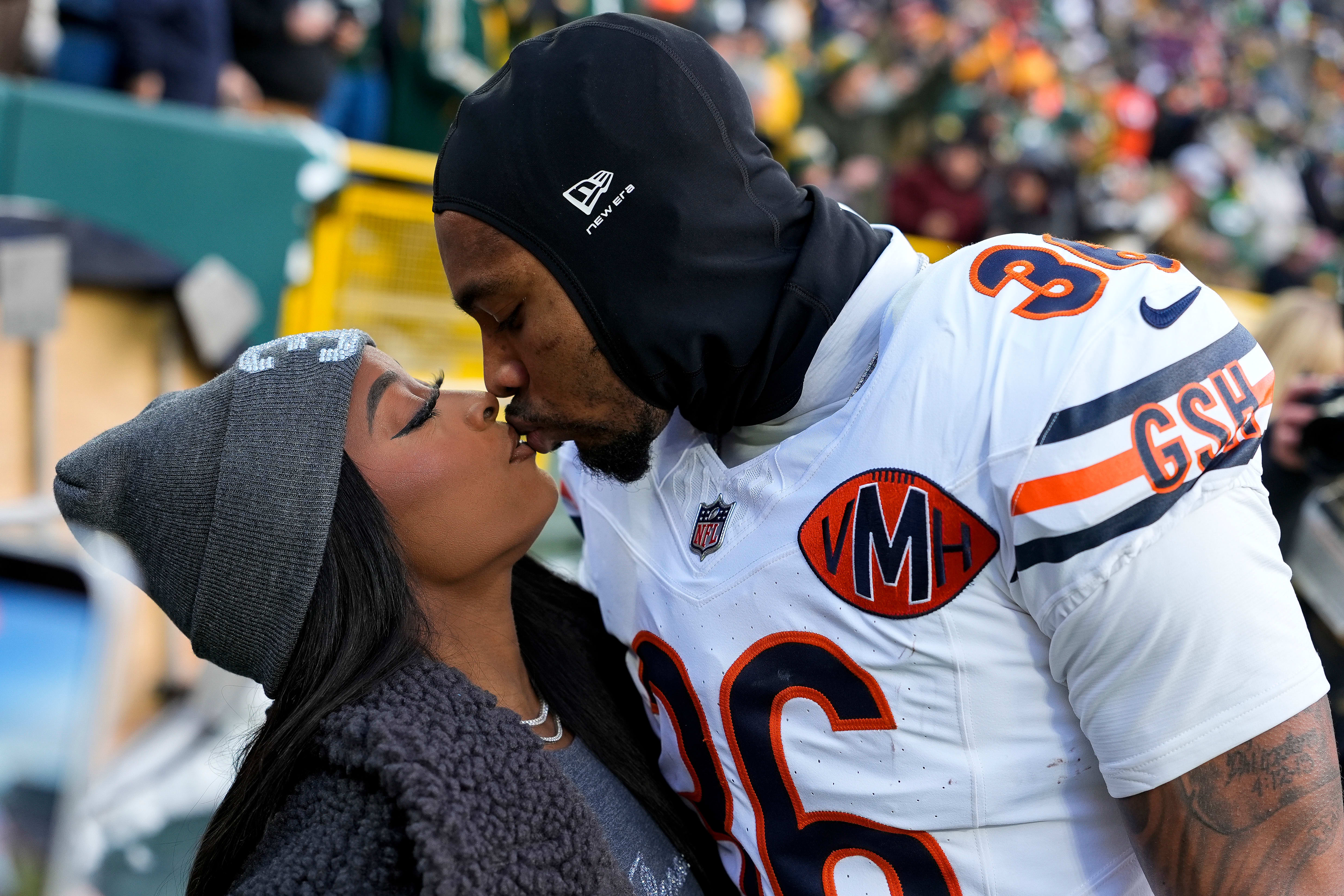 Simone Biles and Jonathan Owens #36 of the Chicago Bears kiss before the game against the Green Bay Packers.