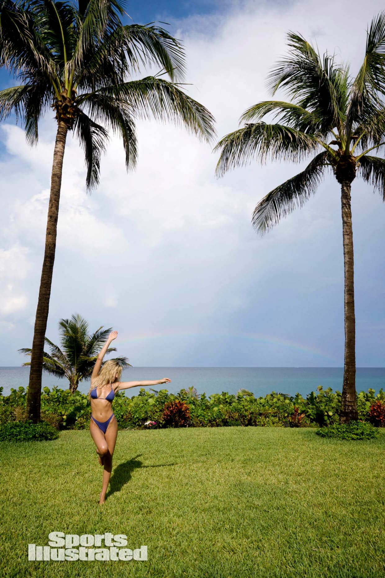 Alix Earle rocks a blue bikini in Florida posing in front of a rainbow with SI Swimsuit.