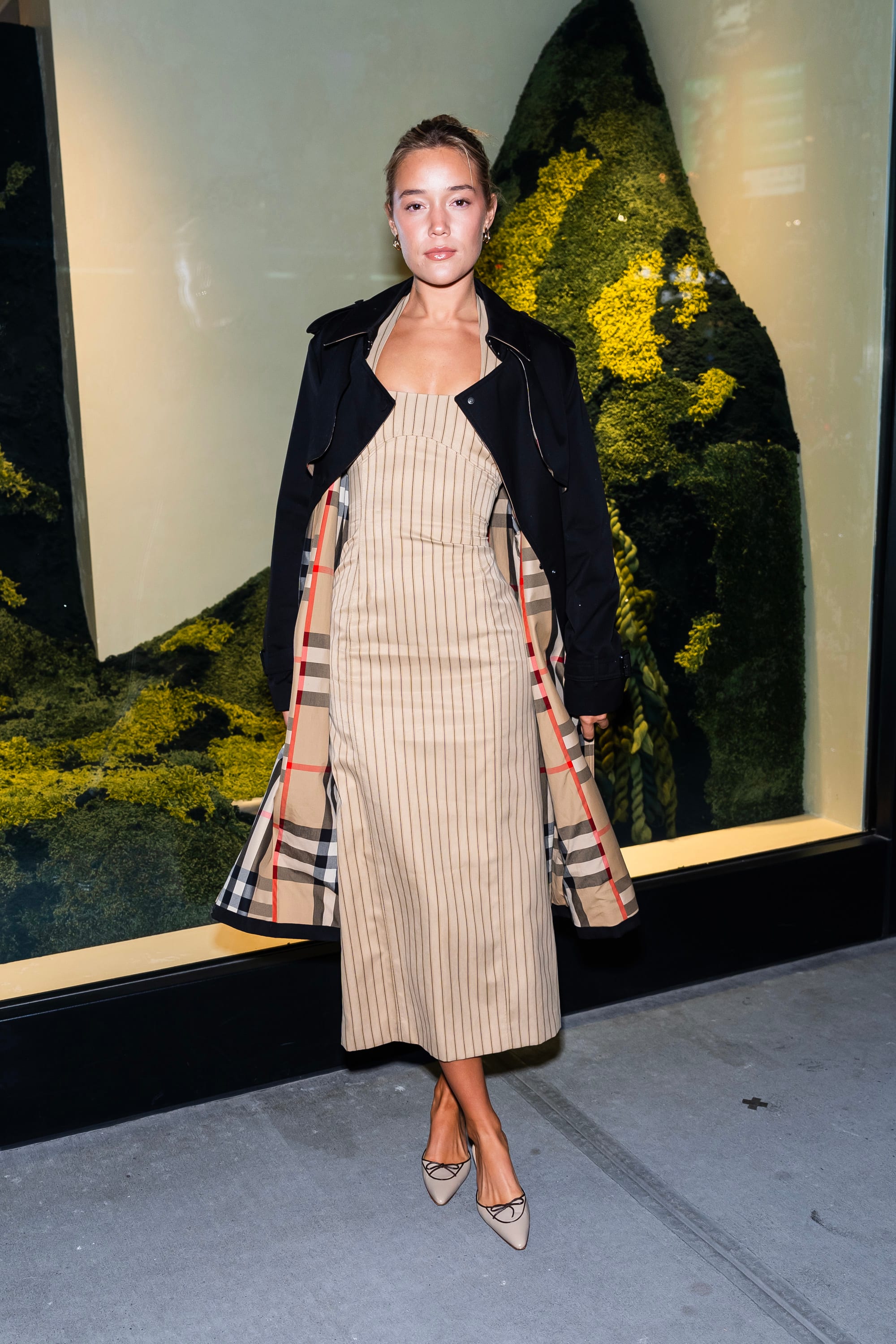 Olivia Ponton wears a khaki striped dress and black coat in New York City.