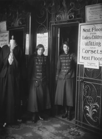 Two lift operators in a London department store, circa 1916.