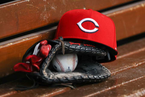 Cincinnati Reds hat and glove sits in dugout.