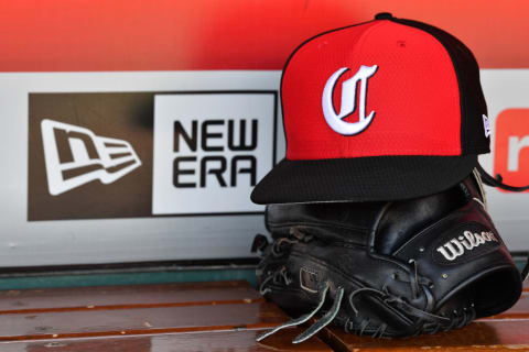 Cincinnati Reds hat and glove sits in the dugout.